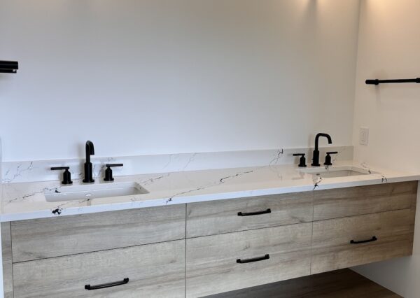 Primary bathroom with double wood vanity and black hardware